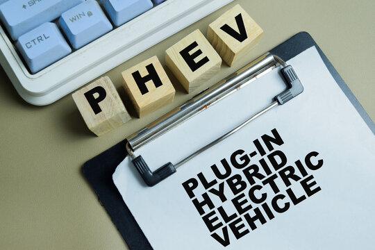Concept of PHEV - Plug-in Hybrid Electric Vehicle write on clipboard isolated on Wooden Table.