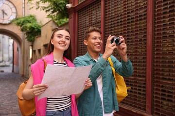 Naklejka premium Travel and tourism. Happy couple with map and camera on city street