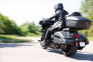 Naklejka premium Man riding motorcycle on road, back view. Motion blur effect
