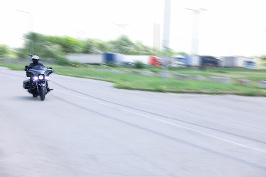 Man riding motorcycle on road, motion blur effect