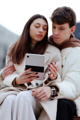 Couple Using a Digital Tablet Together Outdoors Exhibiting Bonding and Interaction © Nikola Spasenoski
