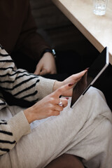 Close-up of a person interacting with a tablet in a casual setting © Nikola Spasenoski