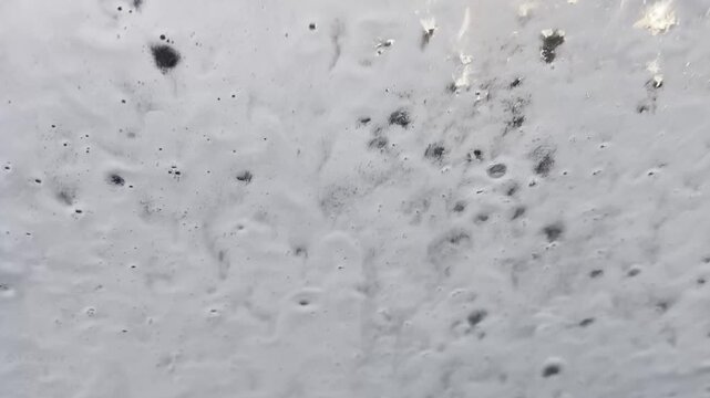 ドライブスルー洗車で車の窓を洗浄する場面