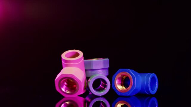 Colorful plastic pipe fittings arranged on reflective black surface