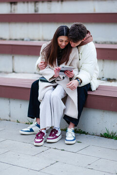 Young couple enjoying time together while looking at a tablet outdoors