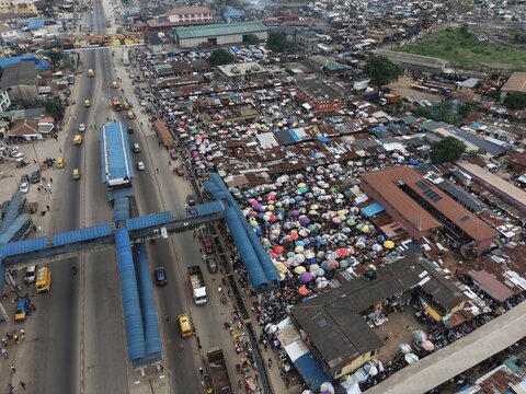 Lagos, Nigeria - 01 August 2026: Aerial view of Abule Egba market with numerous colorful umbrellas, busy street traffic, and dense urban infrastructure in Lagos, Nigeria.