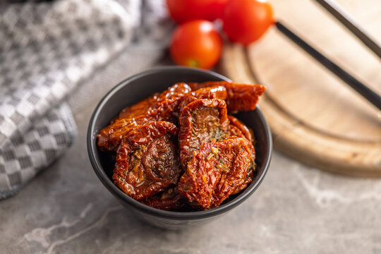 Sun-Dried Tomatoes in Bowl with Fresh Tomatoes on Wooden Board in Rustic Kitchen Setting