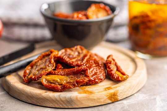 Sun-Dried Tomatoes on Wooden Board With Olive Oil Jar and Bowl, Mediterranean Preserved Ingredient