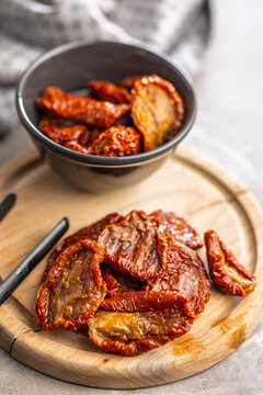 Sun-Dried Tomatoes on Wooden Board With Olive Oil Jar and Bowl, Mediterranean Preserved Ingredient