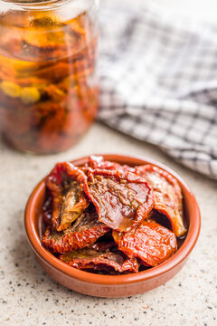 Sun-Dried Tomatoes in Olive Oil in Ceramic Bowl with Jar and Checkered Cloth