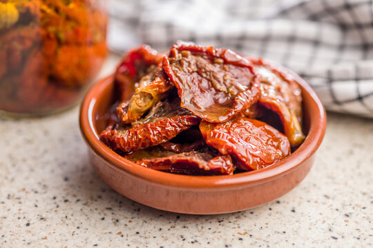 Sun-Dried Tomatoes in Olive Oil in Ceramic Bowl with Jar and Checkered Cloth