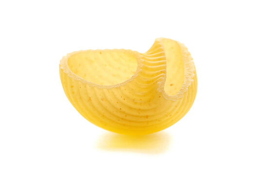 Close up yellow pipe rigate pasta with ribbed, curved shape isolated on white background, side view	