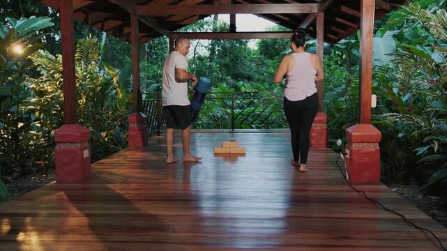 Couple preparing for yoga class in outdoor tropical shala