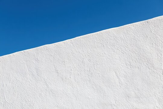Clean white wall texture meets azure sky in a tranquil composition
