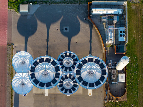 Netherlands - 03 August 2026: Aerial view of an energy hub for alternative fuels including hydrogen, LNG, and electric charging, with circular solar-covered structures and storage tanks.