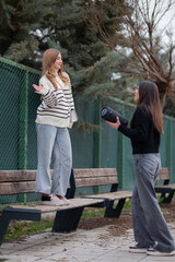 Fototapeta premium Two friends enjoying an outdoor moment with music in a park setting