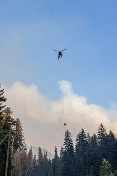 Aerial Firefighting Helicopter Carrying Water Bucket Over Smoke-Filled Forest Near Hope, BC, Canada