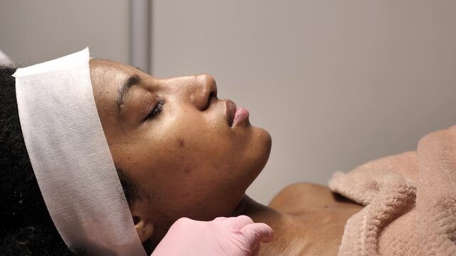 A Black woman receiving a professional facial treatment during Black History Month. Concept of inclusive beauty, self-love, and Juneteenth wellness