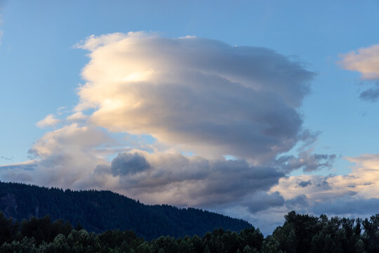 Dramatic Sunset Clouds Over Forested Mountains Near Chilliwack, BC Canada With Soft Evening Light