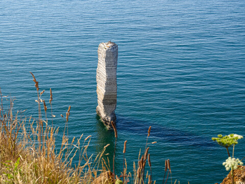 Columna de tiza blanca saliendo del mar azul en la costa francesa de Etretat, viajando por la Normand&iacute;a francesa en verano 2022