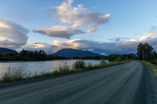 Gravel Riverside Road at Dusk With Mountain View and Dramatic Clouds in Chilliwack, BC, Canada