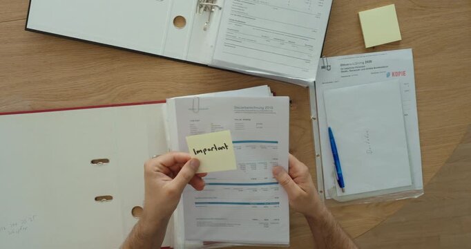 Organizing documents in a binder with an important sticky note. Ideal for office organization, paperwork, filing, and document management concepts.