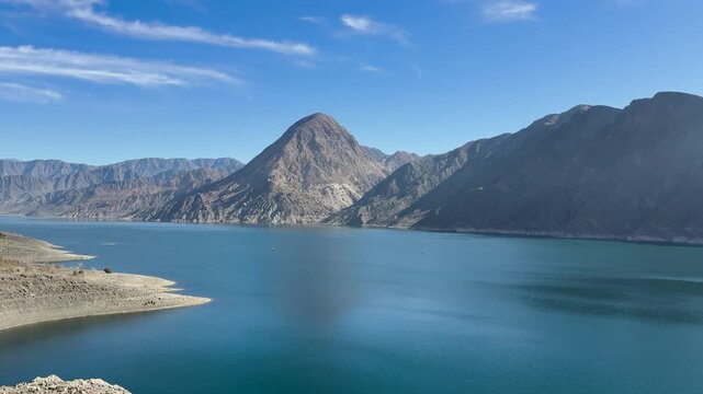 Cerro La Sal rises above Dique Punta Negra, surrounded by rugged precordillera mountains in Zonda, San Juan, Cuyo, Argentina, with the reservoir in the foreground, panning.