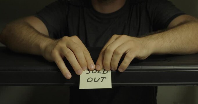 Person placing a sold out sign on an empty shelf. Ideal for retail, inventory shortages, ecommerce, and supply chain concepts.