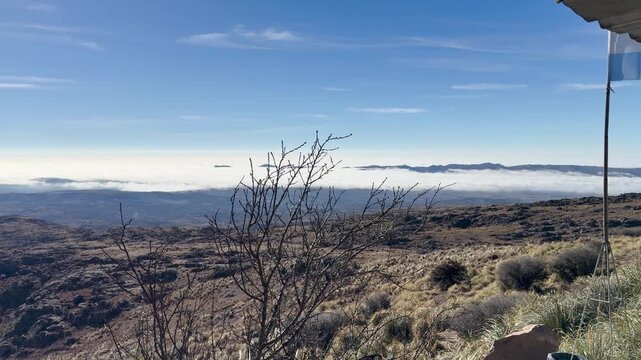 Atalaya highlands overlook a broad cloud-filled valley from the Pampa de Achala plateau in San Alberto, Cordoba, Argentina, with sparse shrubs and rocky terrain, slow pan.