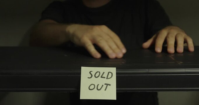 Man feeling along an empty shelf marked with a sold out sign. Ideal for product shortages, retail inventory, supply chain, and ecommerce concepts.