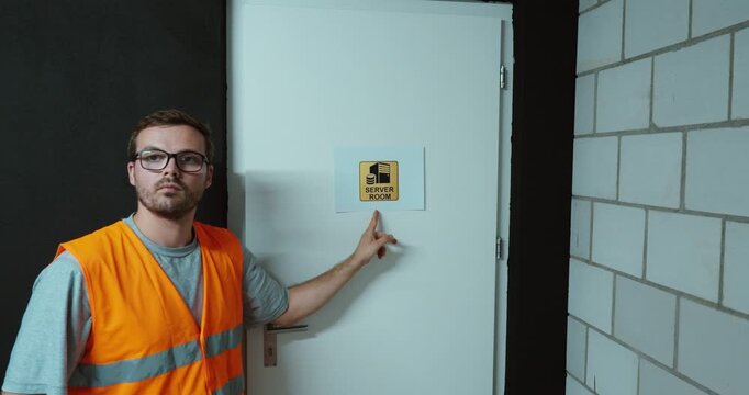 Worker attaching a Server Room sign to a door to indicate a restricted IT and data infrastructure area.