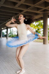 Joyful ballet dancer in blue tutu spinning en pointe under a modern concrete pavilion with expressive movement and natural light © Nikola Spasenoski