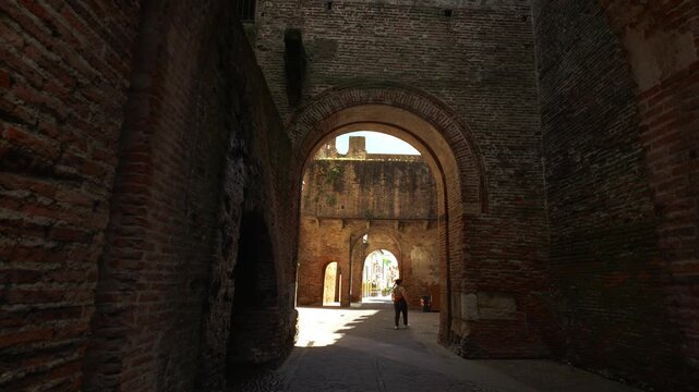 Tourist walking on foot through the grand historic archway into the old town center of Cittadella.