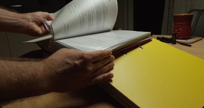 Person searching through multiple binders for a specific document. Ideal for paperwork, document search, office stress and administration.