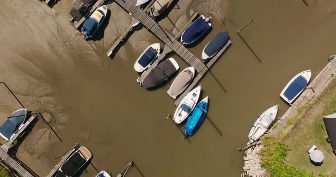 Top down drone view of boats stranded beside a pier in a completely dry harbor, with deeply cracked soil revealing prolonged drought, water scarcity and climate change. Beusichem, Netherlands.