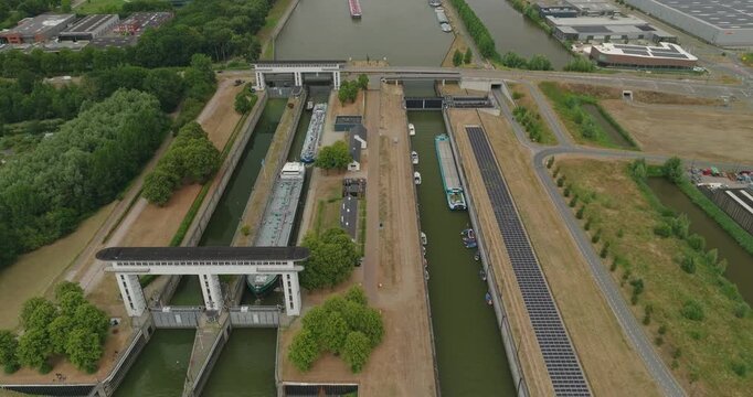 Drone pulls away from a tanker barge waiting inside a sluice lock chamber for the gate to open, revealing another tanker barge waiting on the canal behind it.