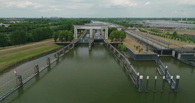 Drone approaches a sluice as its gate opens, revealing a tanker barge waiting inside the lock chamber to pass through and continue its inland journey.