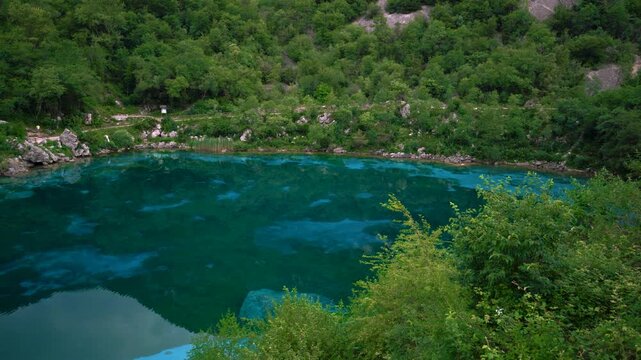 Smooth camera pan revealing the crystal-clear turquoise waters of lake Lago Cornino in Friuli, Italy