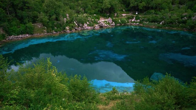 Scenic nature view of Lago Cornino mountain lake. Bright turquoise water and lush green trees and hills.
