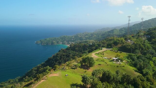 Aerial parallax reveals Top of the World lookout on Mount Dillon above Tobago with panoramic view of Castara Bay coastline and rainforest ridge