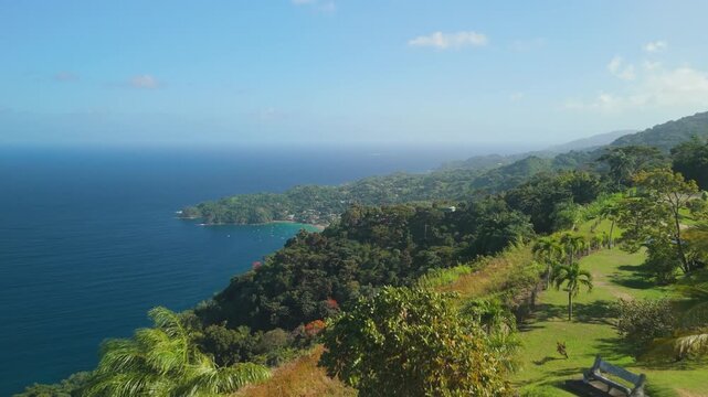 FPV forward flight through hilltop park at Top of the World on Mount Dillon reveals turquoise Castara Bay along Tobago's coastline