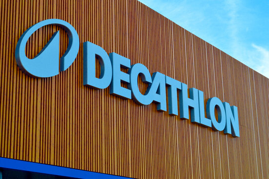 Large blue Decathlon sporting goods retail store sign and corporate logo mounted on modern wooden vertical slat building facade under clear sky