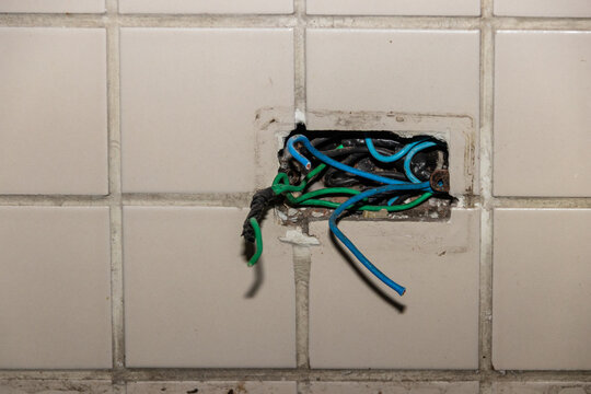 Junction boxes with exposed wiring and hanging colored wires. Focus on home electrical repairs and renovation for stock.