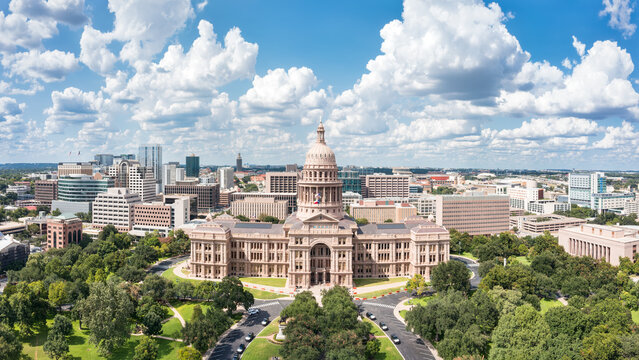 Texas State Capitol, the historic seat of government of Texas and one of the largest state capitol buildings in the United States, with Austin skyline in the background, on a sunny day.