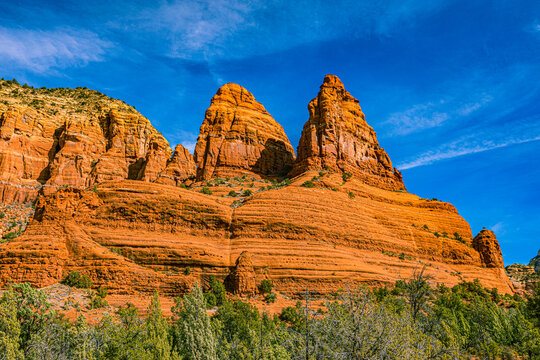 A close-up view of the twin sandstone pinnacles known as The Nuns above a green juniper forest in Sedona.
