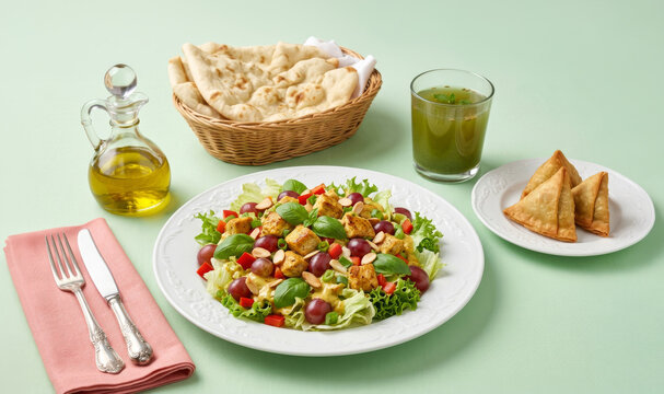 Indian curried chicken salad served with naan bread, samosas, olive oil, and a glass of Jal-jeera 