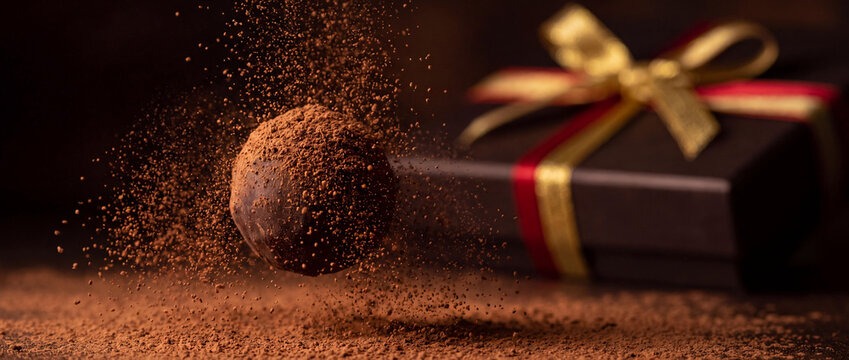Gourmet Chocolate Truffle with Falling Cocoa Powder Dust and Elegant Gift Box Background
