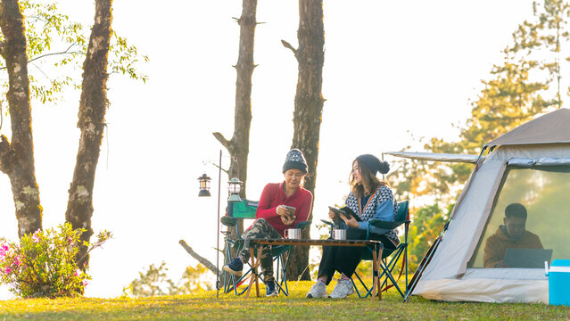 Group of Asian man and woman remote working corporate business meeting discussion while travel nature camping on the mountain with drinking coffee. Digital nomad workation outdoor active lifestyle