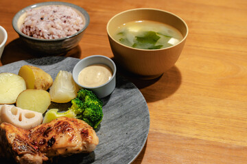 木製テーブルに広がる、鶏肉と旬の野菜を使った和風定食。健康的な食生活を表現 © garcon daily photo