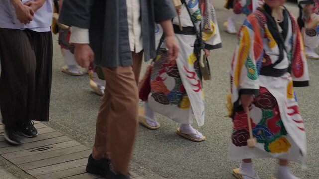 Participants in traditional Japanese attire walking during festival parade on street in Takayama, Japan. Wearing festive costumes, footwear, and the rhythmic movement of procession in autumn season